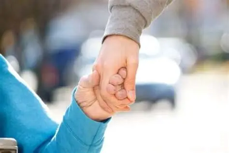 Due persone si tengono per mano, simbolo di assistenza e supporto.
